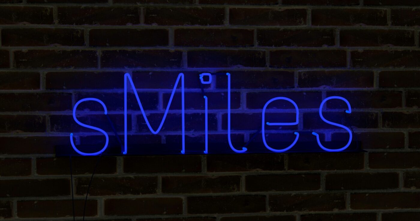 A blue neon sign glowing in daylight (Source: Unsplash - Mariia Shalabaieva)