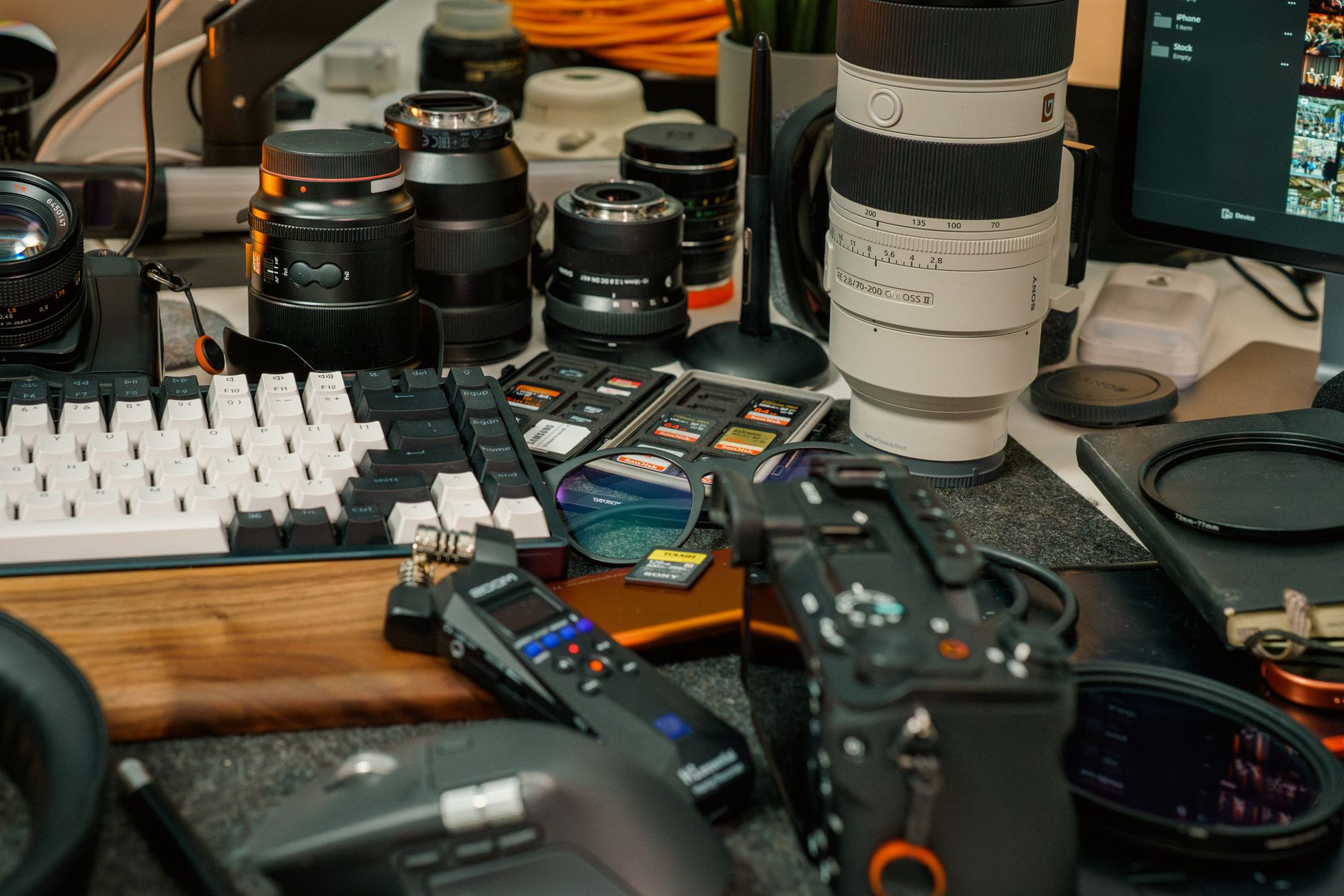 Close-up of a professional photography workstation with lenses, SD cards, and camera gear.